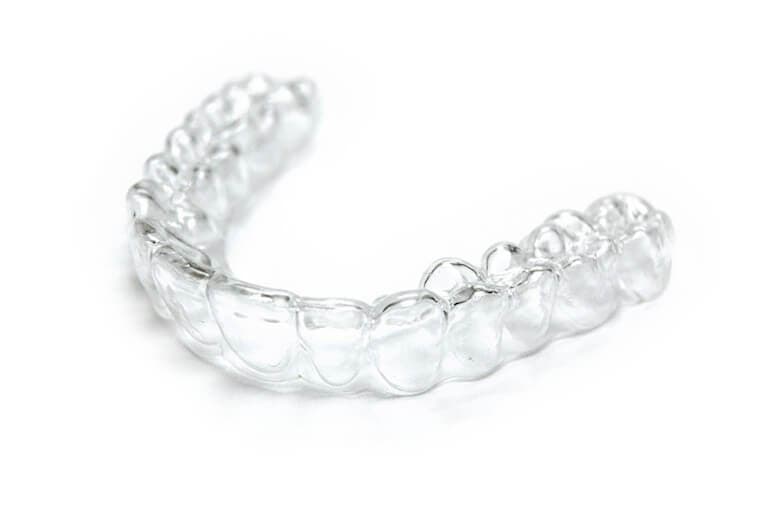 Een doorzichtige Invisalign beugel tussen duim en wijsvinger
